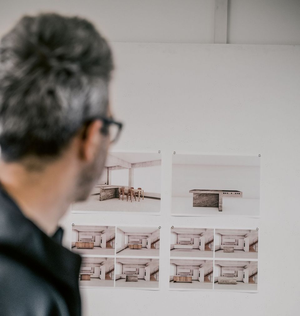 Caesar Zumthor from behind, looking at architect's documents on the wall