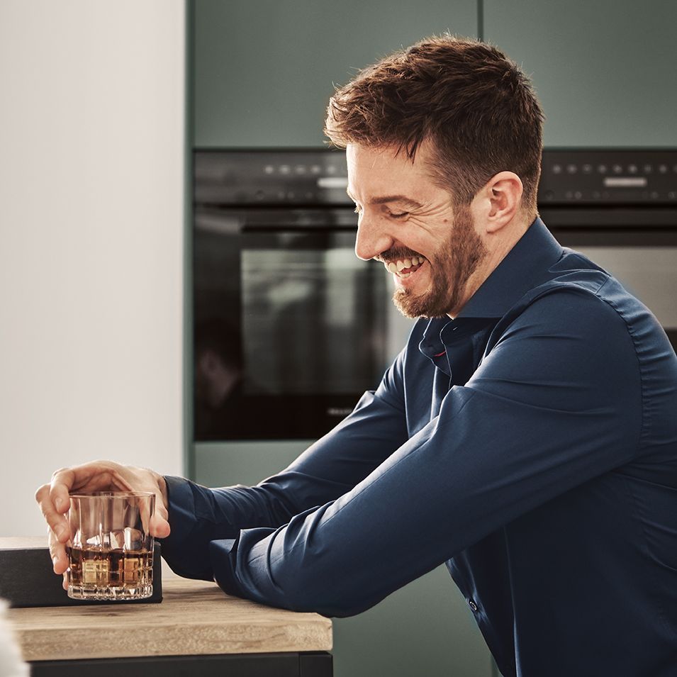 Laughing man with whiskey glass in next125 kitchen