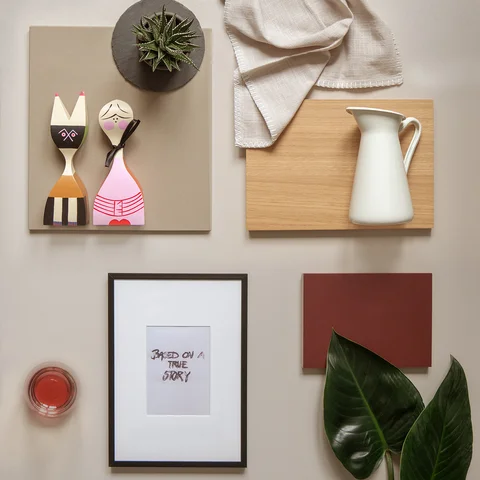 Moodboard mit Holzbrett, Stoff, Keramikkanne, Pflanzenblatt, Dekofiguren, Farbmuster und Bilderrahmen.